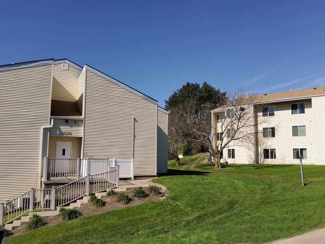 two apartment buildings on the side of a grass field